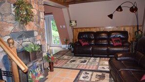Una sala de estar acogedora con chimenea de piedra, sofás de cuero y suelo a cuadros.