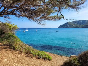 A coastal landscape with clear blue sea, boats, and a hilly backdrop. - Apartment 4B Formentor sea view & pool in Cañamel (Capdepera)