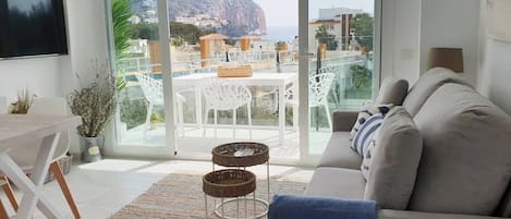 Una sala de estar moderna con un sofá, un televisor y un comedor con sillas y una mesa.