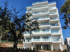 Un hôtel à plusieurs étages doté de balcons, avec un arbre au premier plan et un ciel bleu dégagé.