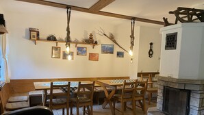 Un comedor acogedor con mesas y bancos de madera, una chimenea de piedra y luces fijadas a la pared.