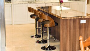 A kitchen with a wooden island, three bar stools, and a microwave. - Glenshane Country House (Maghera)