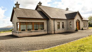 A two-story house with a stone facade, large windows, and a gravel driveway. - Glenshane Country House (Maghera)