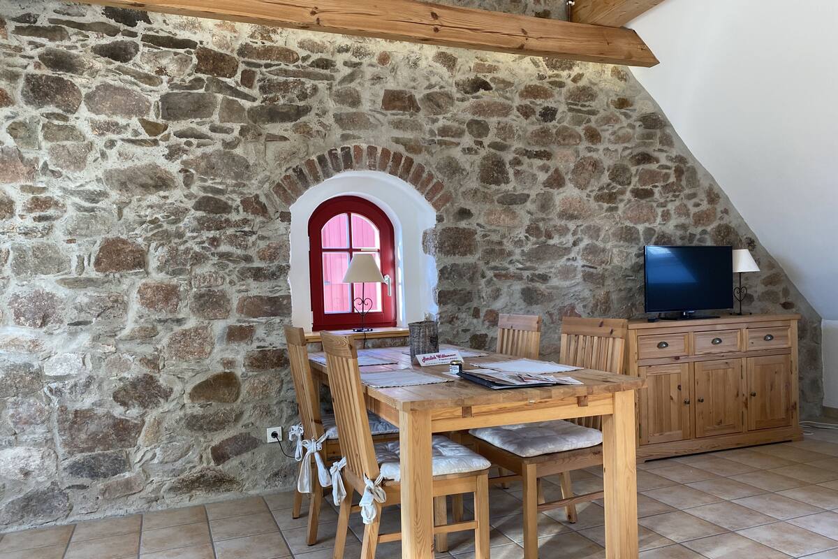Un coin repas chaleureux avec un mur en pierre, des meubles en bois et un téléviseur.