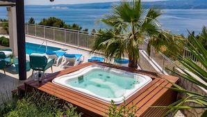 Ein Whirlpool auf einer Holzterrasse mit Blick auf das Meer.