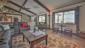 A spacious living room with a large sectional sofa, a wooden coffee table, and a view of the outdoors through large windows. - Desert Oasis with Pool, Fire Pit, Game Room, and Dry Bar (Borrego Springs)