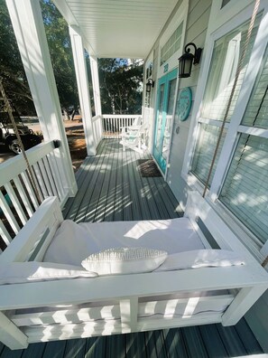 Relax on the covered porch with a white rocking chair and a comfortable bench.