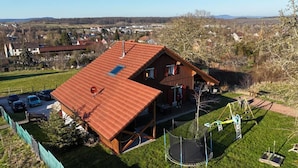 A two-story house with a red roof, a visible attic, and a trampoline in the backyard. - Le Chalet au Vieux Vignoble, a spacious cottage in Alsace near Saverne, offers c (BOUXWILLER)