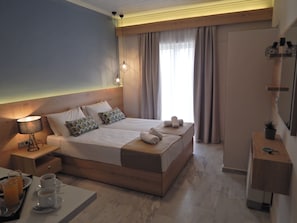 Una habitación de hotel moderna con una cama grande, mesitas de noche, un escritorio y una ventana con cortinas.