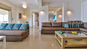 A modern living room with two sofas, a coffee table, and a view into the kitchen. - Infinite Blue Epidavros (Palaia Epidavros)