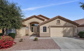 A two-story house with a beige exterior, a garage, and a driveway.