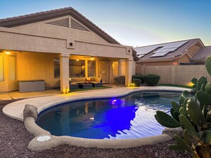 Propiedad residencial con piscina, zona de estar exterior y patio cubierto.