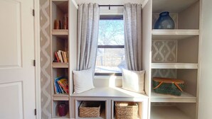 A cozy reading nook with a built-in bench, shelves, and storage baskets. - Cardinal House: Foseball, Sunroom, 6ft Fence, King Bed, Near Hospital & BassPro (Springfield)