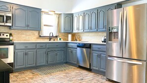 A kitchen with grey cabinets, stainless steel appliances, and a patterned floor. - Cardinal House: Foseball, Sunroom, 6ft Fence, King Bed, Near Hospital & BassPro (Springfield)