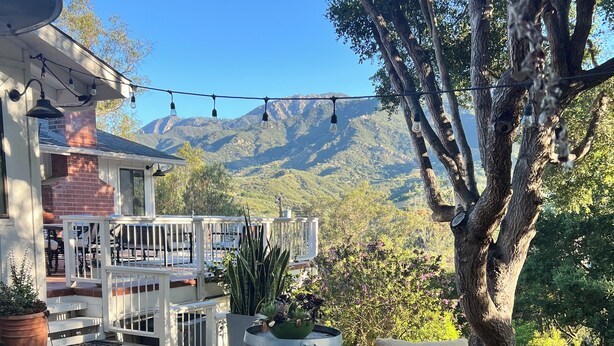 Um pátio com mobiliário de exterior, um vaso grande e vista para montanhas.