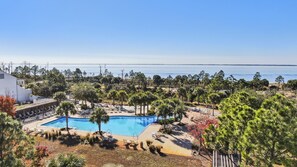 Un resort con una piscina grande, sillas de descanso y vistas al océano.