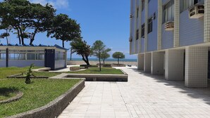 A pathway leading to a building with a view of the sea. - Furnished apartment on Avenida Boa Viagem, beachfront condominium. (Recife)