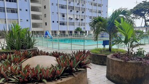 A rooftop pool area with a blue slide, surrounded by potted plants and a modern building in the background. - Furnished apartment on Avenida Boa Viagem, beachfront condominium. (Recife)