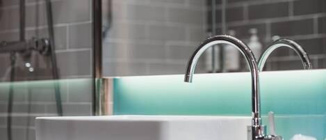 A modern bathroom with a white sink, chrome faucet, and a glass shower enclosure.