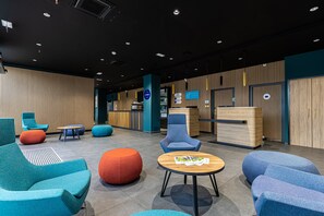 A modern lobby with seating areas, a reception desk, and a wooden panel wall. - Holiday Inn Express Ajaccio by IHG (Ajaccio)
