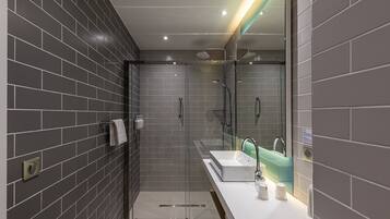 A modern bathroom with a glass-enclosed shower, a white sink, and a large mirror.
