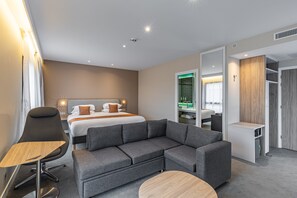 A modern hotel room with a bed, grey sofa, round coffee table, and a walk-in closet. - Holiday Inn Express Ajaccio by IHG (Ajaccio)