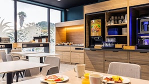 A modern hotel dining area with breakfast options, a coffee machine, and a view of the outdoors. - Holiday Inn Express Ajaccio by IHG (Ajaccio)