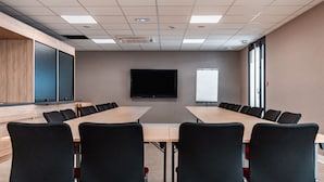 A conference room with a long table, black chairs, a flat-screen TV, and a whiteboard. - Holiday Inn Express Ajaccio by IHG (Ajaccio)