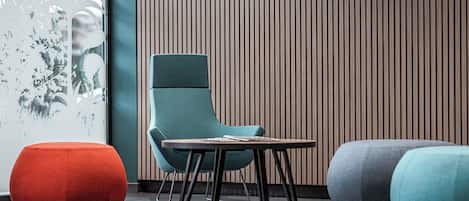 Un interior moderno con una silla verde azulada, una mesa de madera y dos otomanas rojas y azules.