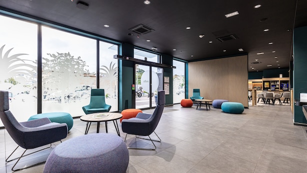 A modern interior with seating areas, large windows, and a reception desk. - Holiday Inn Express Ajaccio by IHG (Ajaccio)