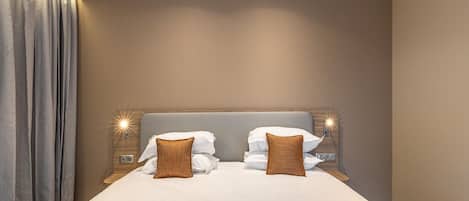 Habitació d'hotel amb un llit gran, dues làmpades laterals i un capçal de llit.