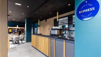 Een modern café met een balie, een zithoek en een bord waarop staat Express Café & Bar.