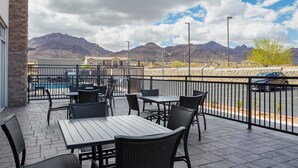An outdoor patio with tables and chairs, a pool, and mountains in the background. - Holiday Inn Express and Suites El Paso North by IHG (El Paso)