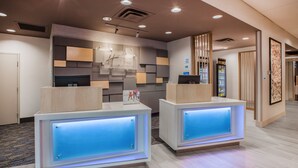 A reception area with two reception desks, a modern wall design, and a vending machine. - Holiday Inn Express and Suites El Paso North by IHG (El Paso)