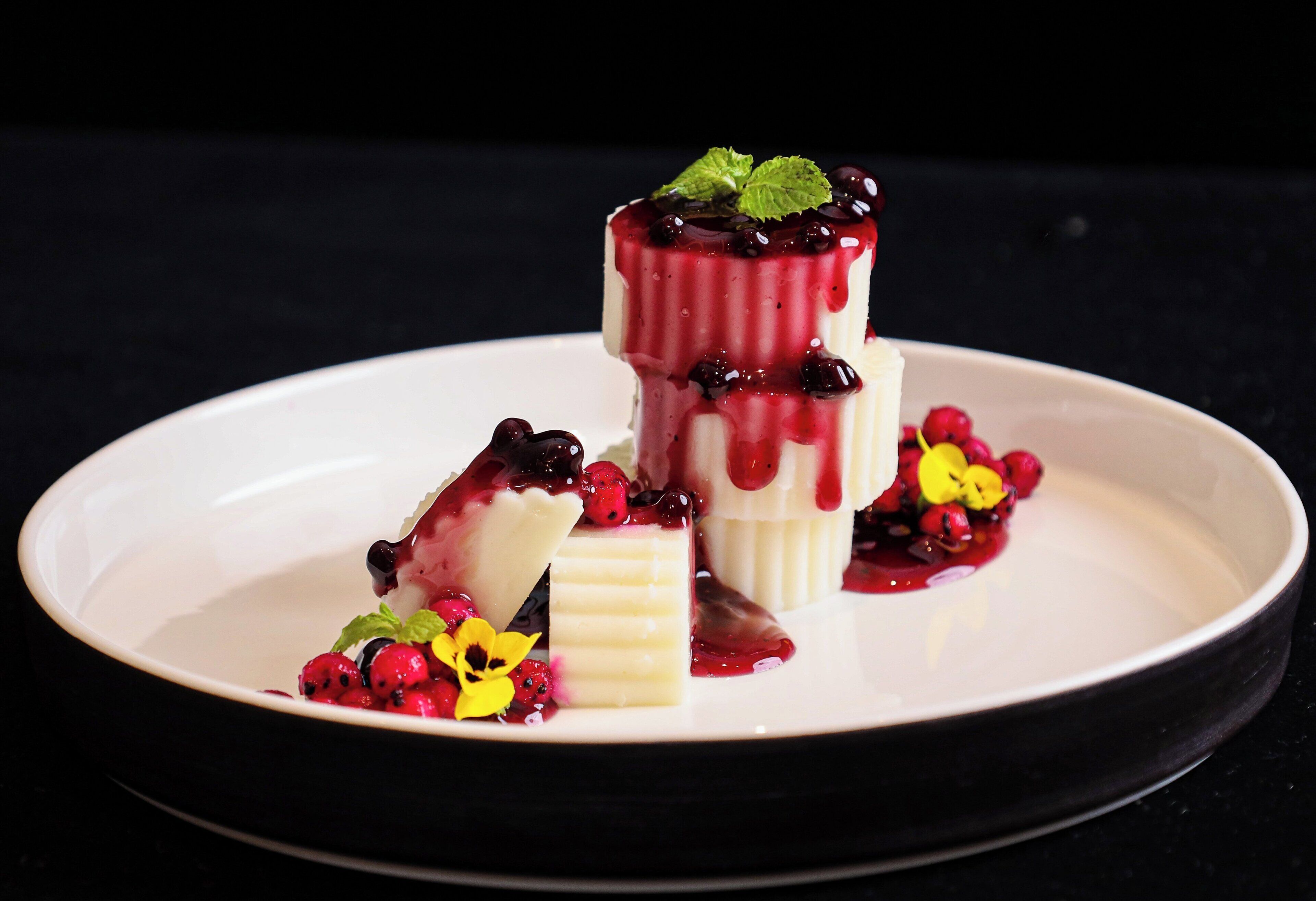 A dessert with berries and mint on a white plate.