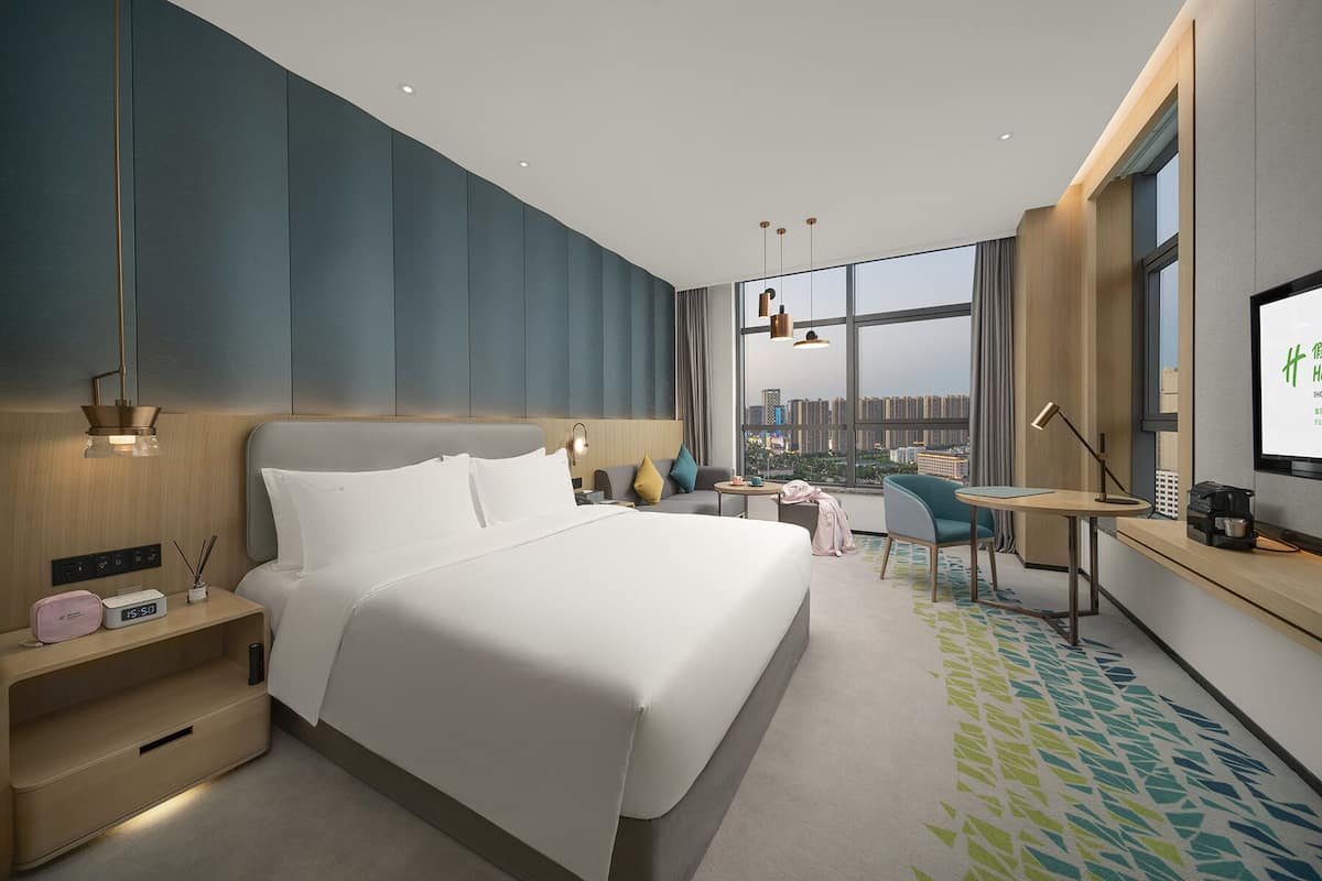 Une chambre d’hôtel moderne équipée d’un grand lit, d’un bureau, d’une chaise et d’un téléviseur.