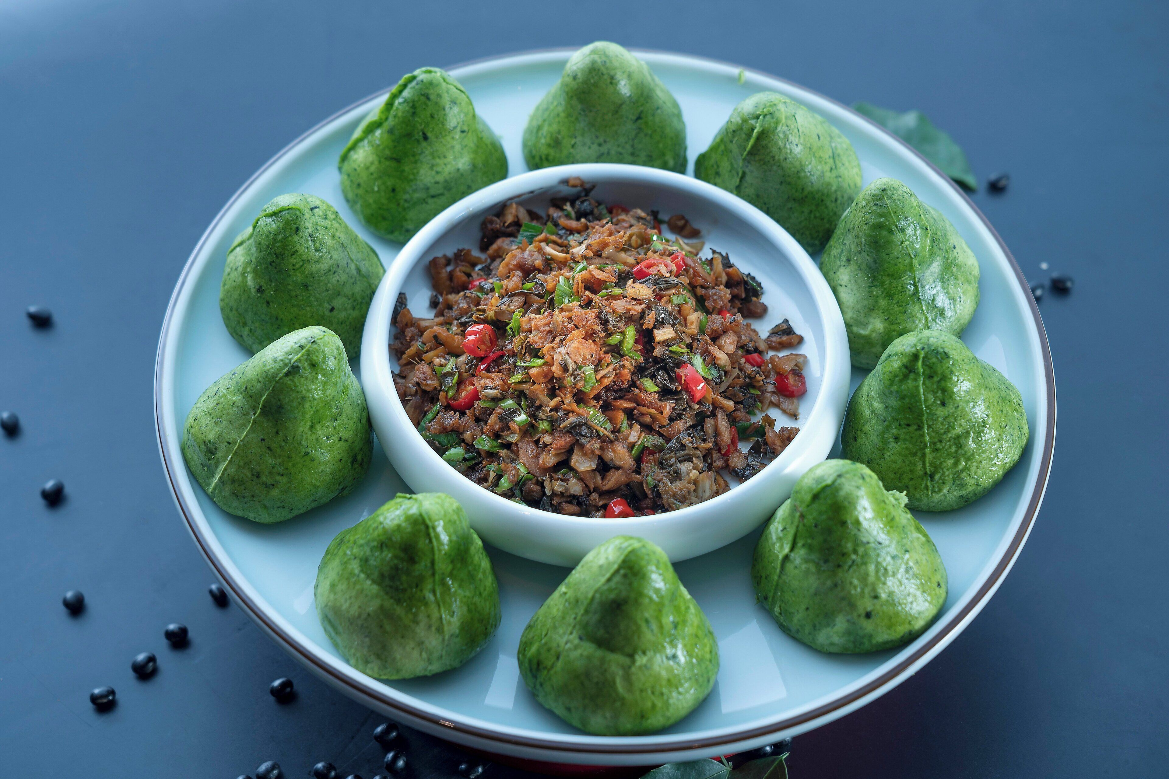 A plate of food with a central bowl surrounded by green items.
