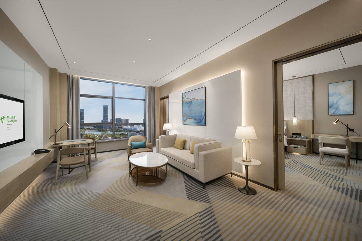 Une chambre d’hôtel moderne dotée d’une grande fenêtre, d’un canapé, d’une table basse et d’un bureau.