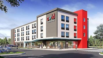 Un hotel moderno con una fachada llamativa en rojo y gris, varios pisos y un área de entrada cubierta.