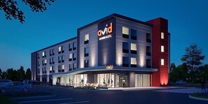 Um hotel moderno com um letreiro 'avid' bem visível, vários andares e uma entrada bem iluminada.