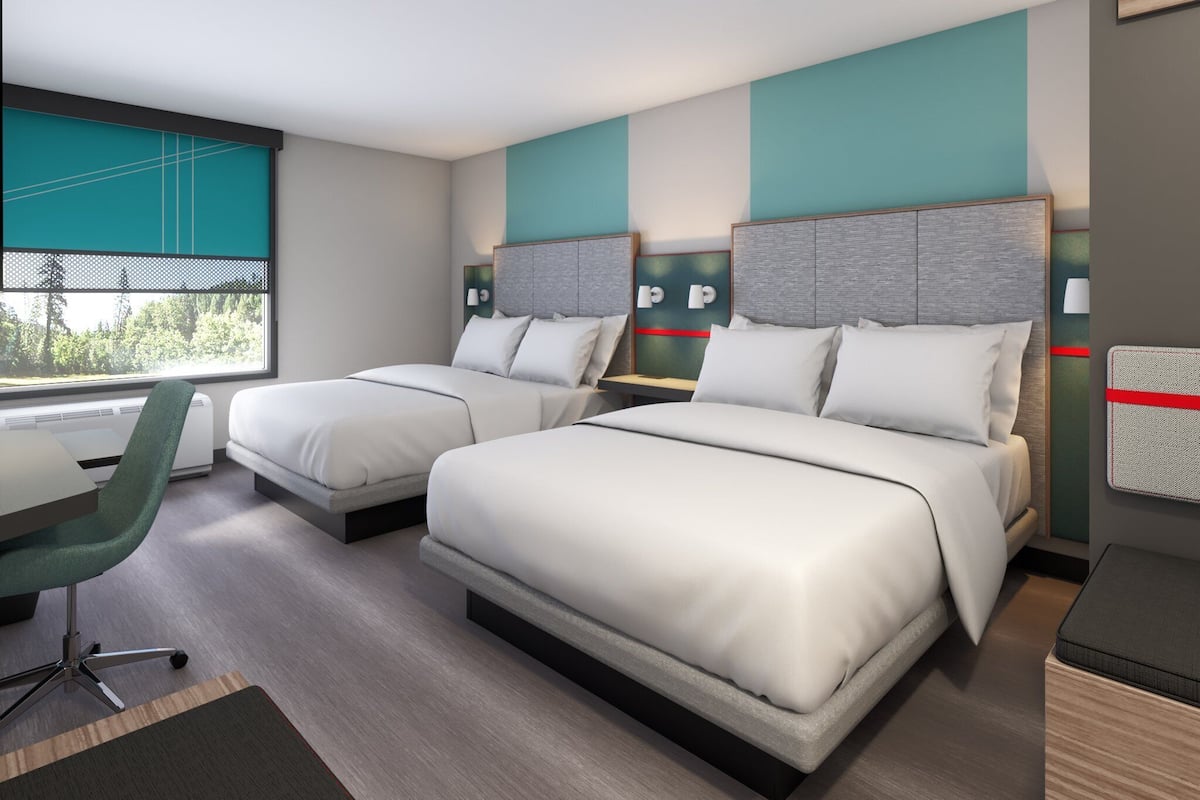 A modern hotel room with two beds, a desk, and a chair.