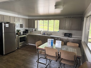 Une cuisine équipée d’un réfrigérateur, d’une cuisinière, d’un four à micro-ondes et d’un coin repas avec des chaises et une table.