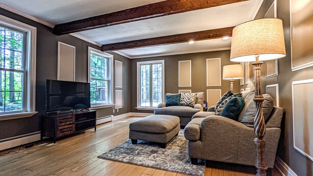 Ein Wohnzimmer mit Fernseher, zwei Sofas, einem Couchtisch und einer Stehlampe.