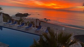 A poolside view with lounge chairs and a sunset over the ocean. - Casa Alvarado | Beachfront Private Escape w/ Pool (Baja California Sur)
