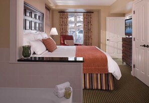 Cozy retreat with a neatly made bed, side table, and window with curtains.
