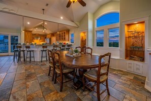 A spacious kitchen with a large island, bar stools, and a dining table with chairs. - Corolla Oceanfront 14BR Estate | Pool, Elevator, Pet-Friendly | Sleeps 30 (Corolla)