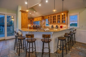 A kitchen with wooden cabinets, a central island with stools, and a large window.