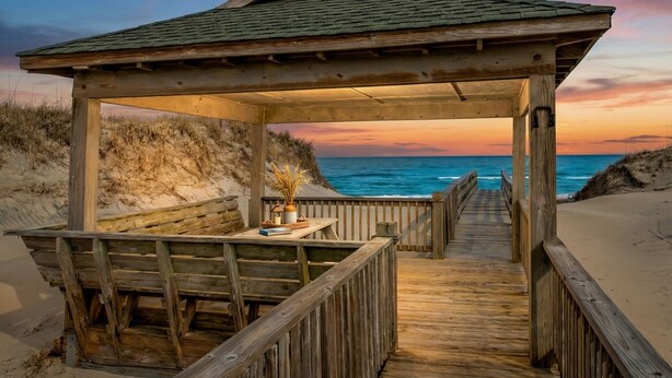 A wooden beach gazebo with a bench and a table, overlooking the ocean. - Oceanfront Estate | 14BR | Private Pool & Hot Tub | Sleeps 32 (Corolla)