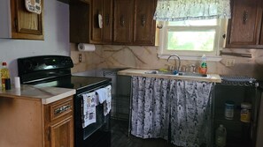 A kitchen with wooden cabinets, a stove, a sink, and a window with a curtain. - Middle of Dallas/Fort Worth! WORLD SERIES, RANGERS, COWBOYS, MAVS, CONCERTS!! (Irving)