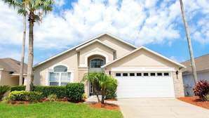 A two-story house with a garage, surrounded by palm trees and well-maintained landscaping.